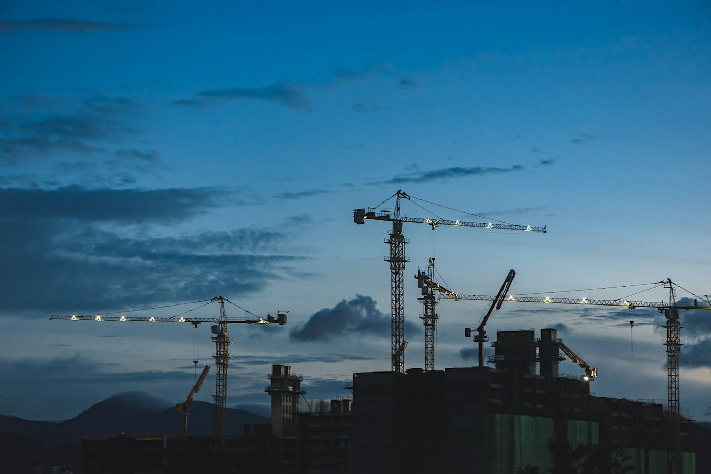 Grues de chantier se découpant sur un ciel de crépuscule